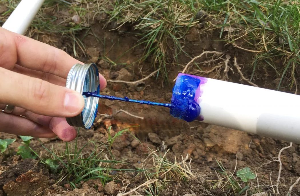 applying blue cement to connect irrigation system pipes