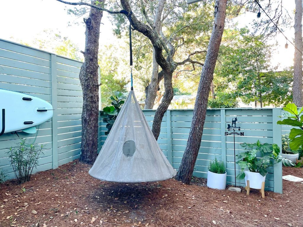 Side yard area with hanging tent swing near fence