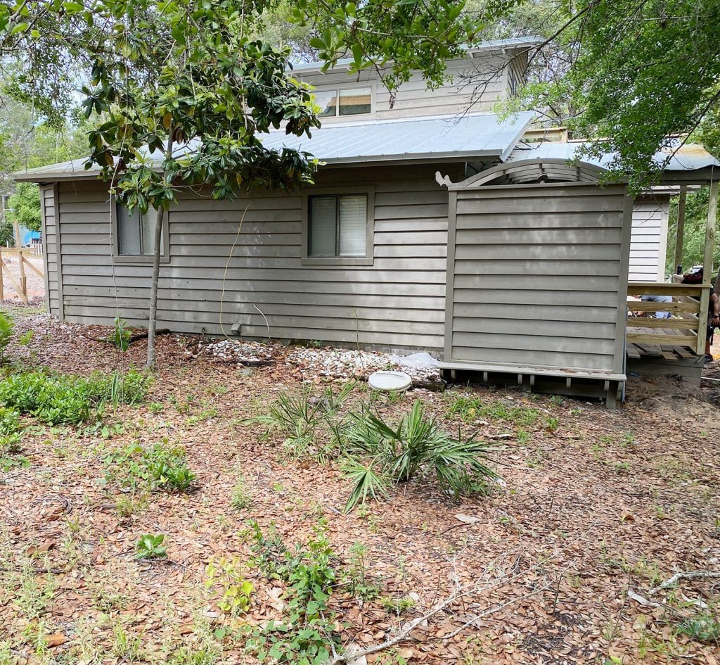 Before photo of back of house with brown paint and empty yard