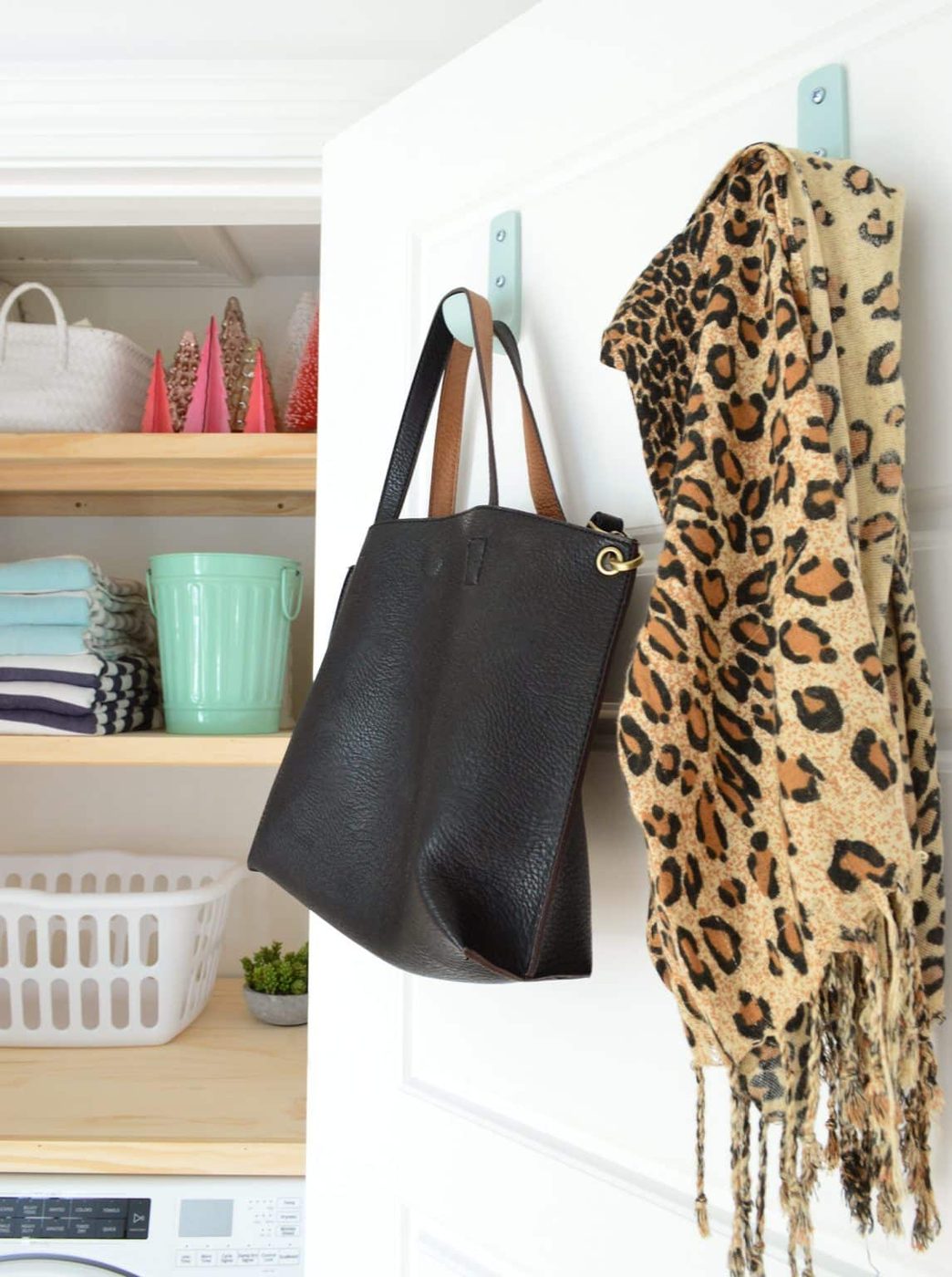 Laundry closet door with large colorful hooks with Hands-on laundry shelves in background