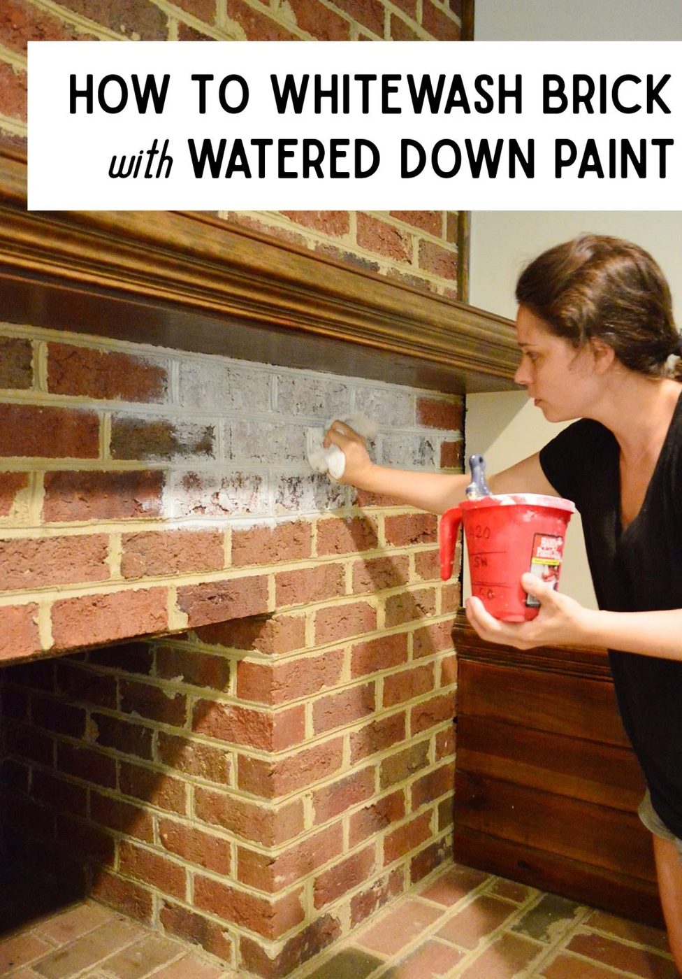 Sherry dabbing watered down paint onto red brick fireplace for whitewash effect