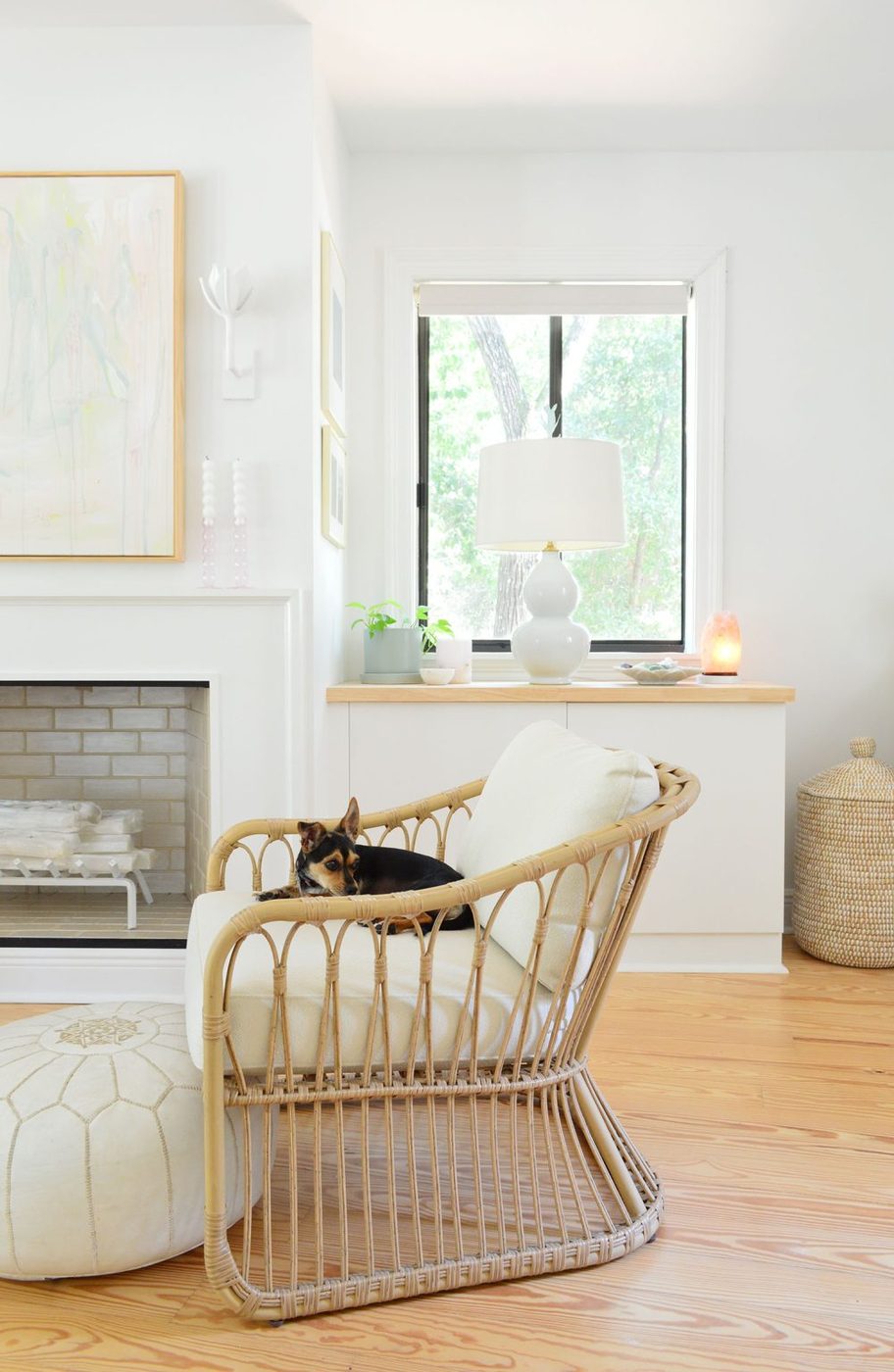 Wicker chair in bedroom with dog sitting on it in front of fireplace
