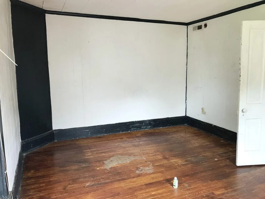 Before Photo Of Main Bedroom With Dark Green Trim Covering Corner Fireplace