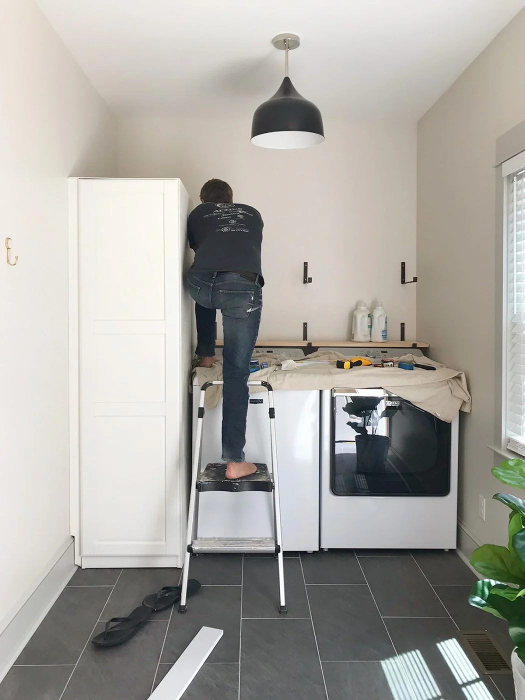 john leaning over top loading washer to screw in shelf brackets