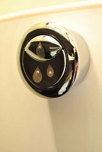 Dual flush toilet flush button on side of toilet tank