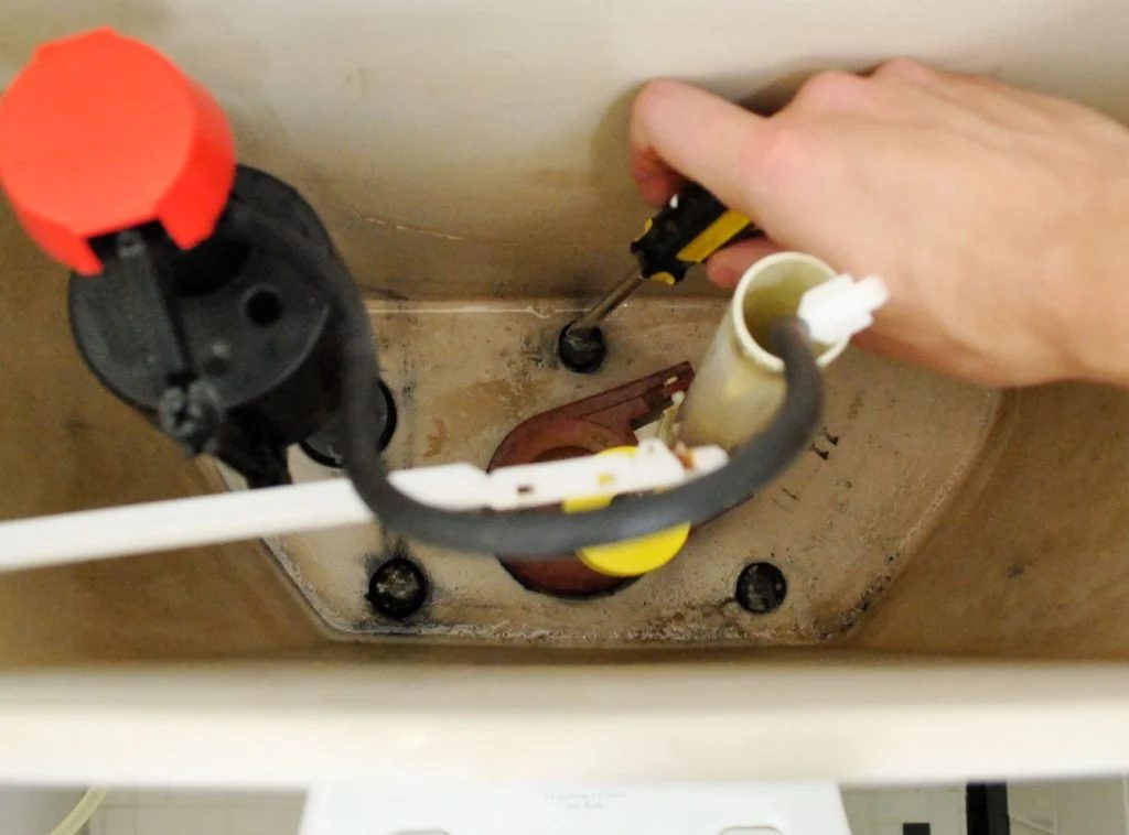 Hand Unscrewing Bolts Inside Toilet Tank