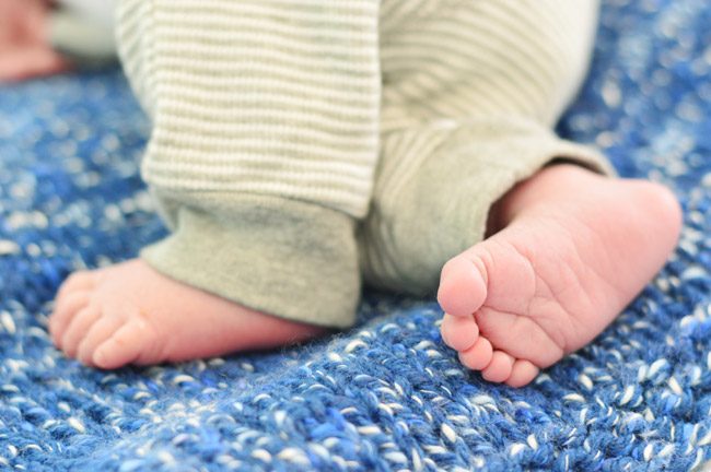 Hands-on Newborn Photo Of Infant Feet On Blue Blanket For Birth Announcement