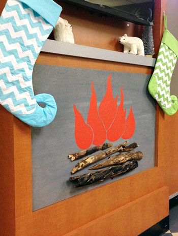 Wrapped up faux fireplace with holiday decorations and stockings on mantle for Childrens Hospital of Richmond waiting room