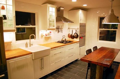 A White Kitchen Alongside Butcher Block And An Apron Sink