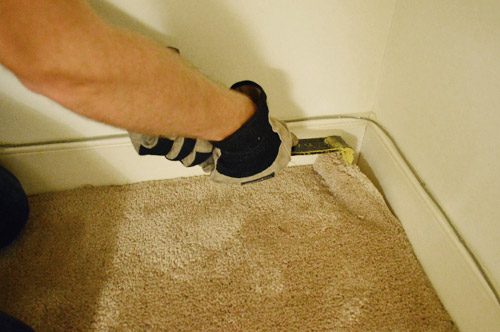 removing carpet with crowbar in corner