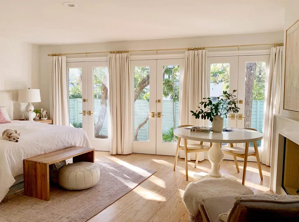 Bedroom with three french doors with with curtains and sunlight coming in