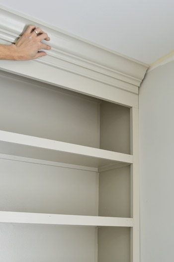 Hand holding crown molding piece in place on Hands-on bookshelf