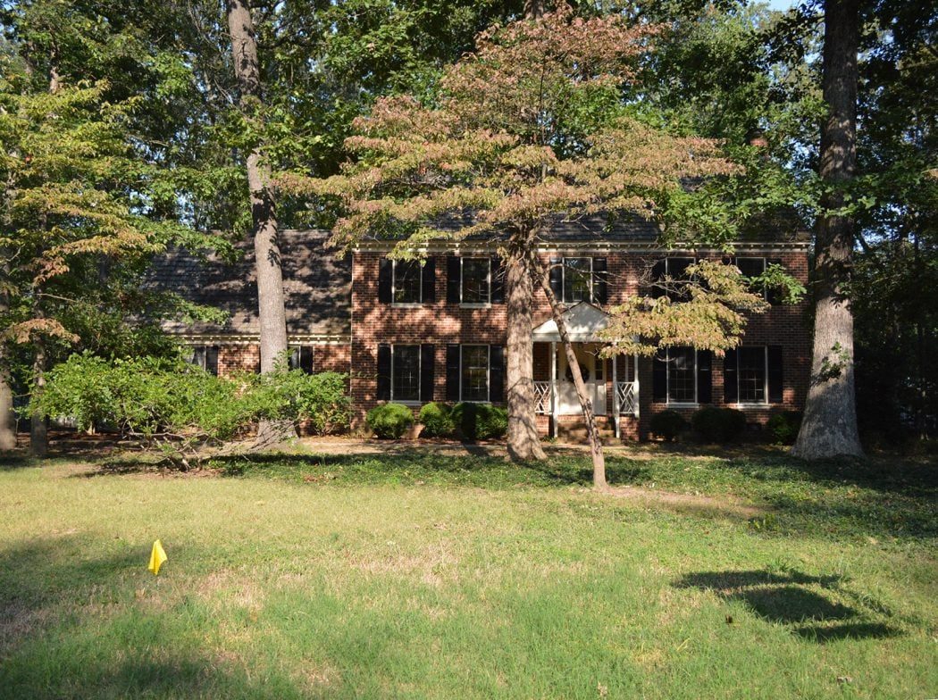 before photo of brick house covered by trees