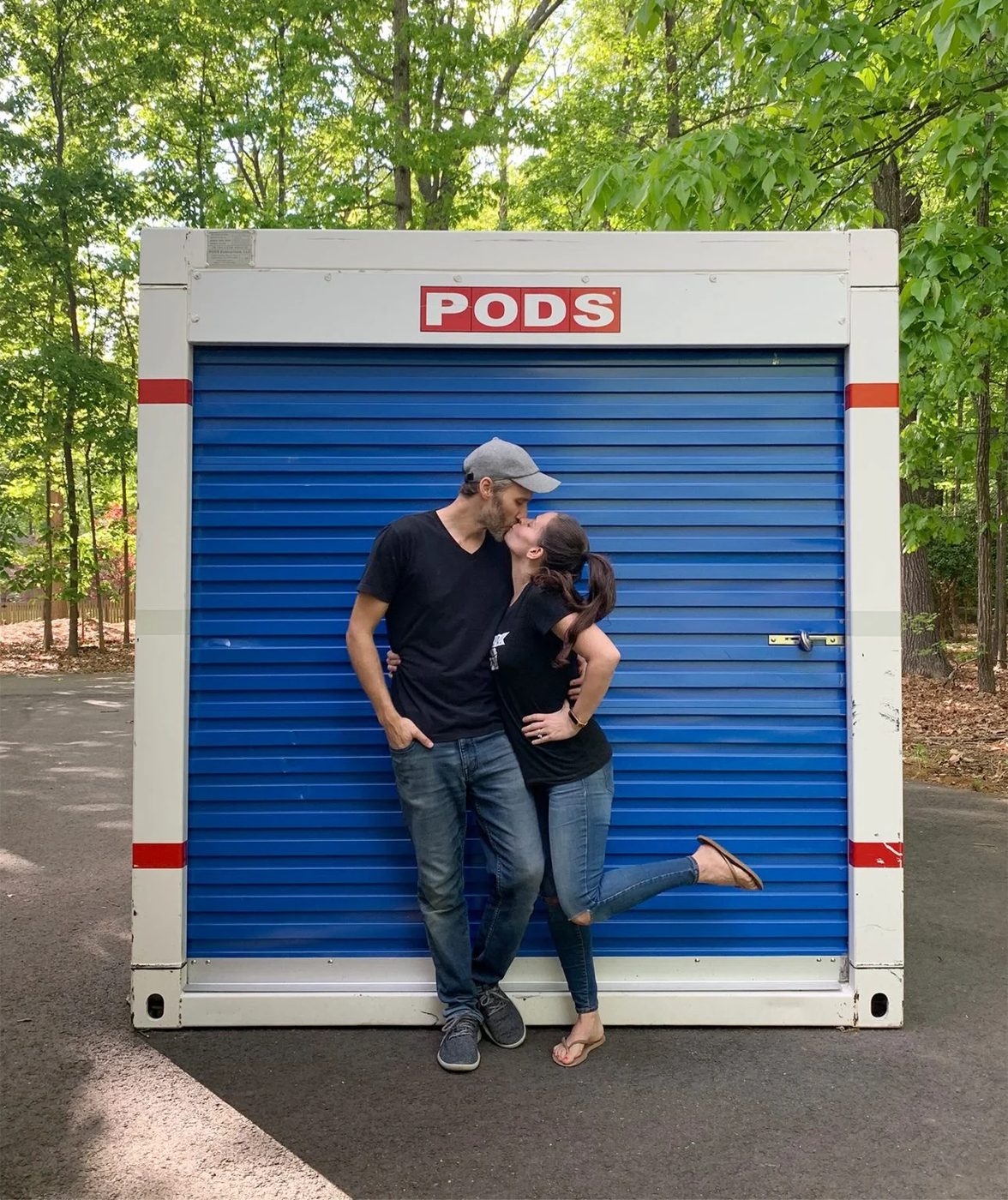 The house team kissing in front of moving PODS storage container