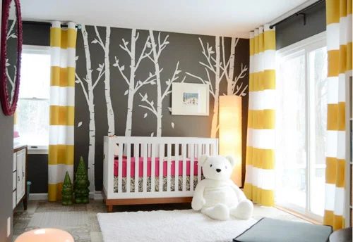 A Dark Gray Nursery Alongside A Tree Mural & Striped Curtains