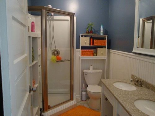 A Dark Blue Bathroom Alongside A Corner Shower