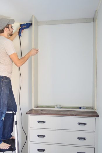 Man screwing into the side of a homemade Hands-on bookshelf