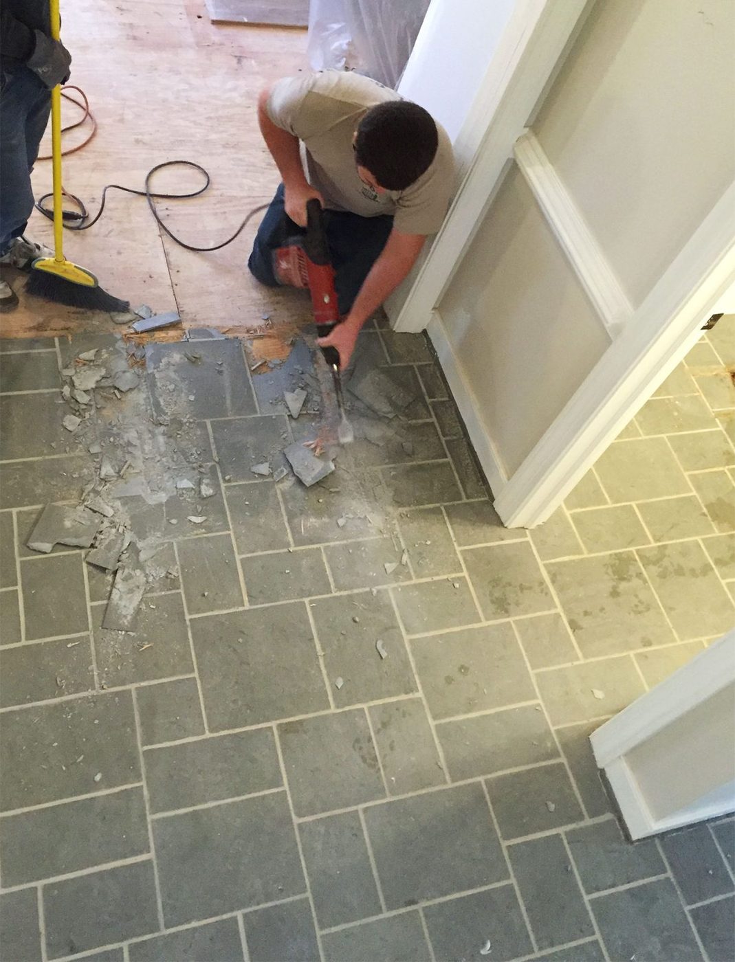 Man Using Demolition Hammer To Remove Slate Floor