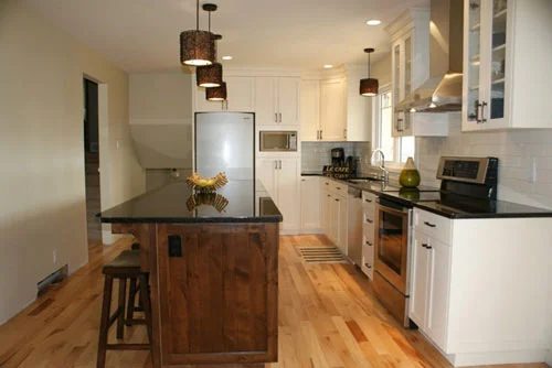 A Kitchen Alongside A Dark Wood Island And White Cabinets