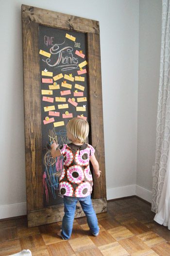 Toddler girl drawing on Hands-on leaning chalkboard with Thanksgiving gratitude notes