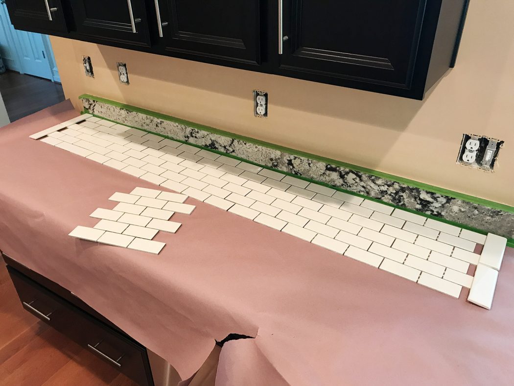white subway tile sheets laid out on counter to finalize placement