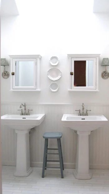 A Luxe White Bathroom Alongside Pedestal Sinks