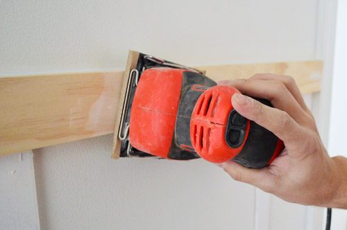 using Black & Decker palm sander to smooth wood filler and spackle in Hands-on molding installation