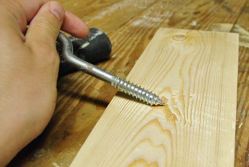 scraping course screw across new wood board to create distressed effect for Hands-on project