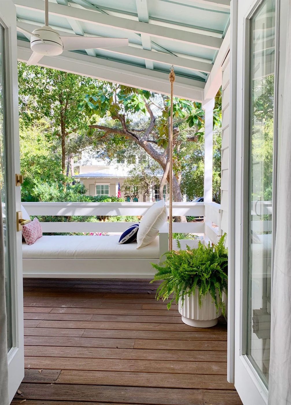 View Of White Hanging Daybed Swing Under Covered Porch Through Open French Doors