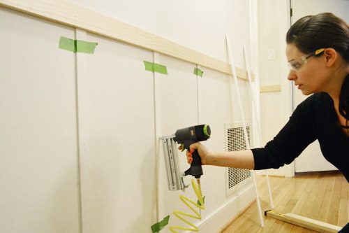 wearing safety goggles and using Craftmans nail gun to install vertical lattice strips to create battens in board and batten Hands-on project