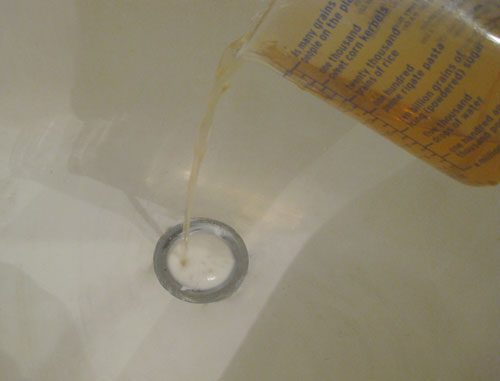 pouring vinegar and baking soda in clogged bathroom drain