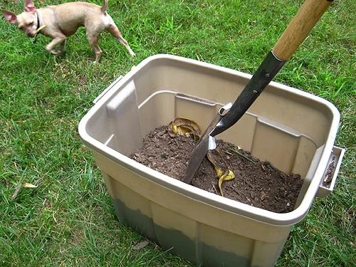 stirring homemade compost bin with shovel