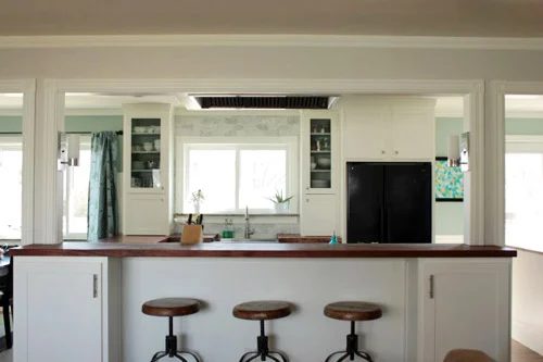 A Kitchen Alongside Glass Cabinets, Wood Counters & A Marble Backsplash