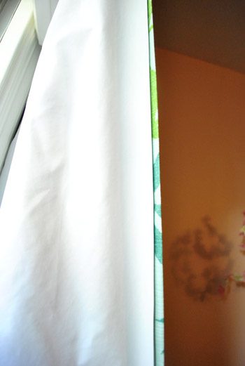 close up of blackout curtain liner fabric placed behind curtain panel in a girl's nursery