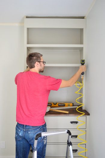 Man nailing trim pieces on the face of Hands-on bookshelf