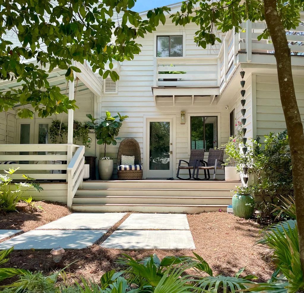 Front Of White Modern House With Plenty of Greenery With Large Concrete Walkway