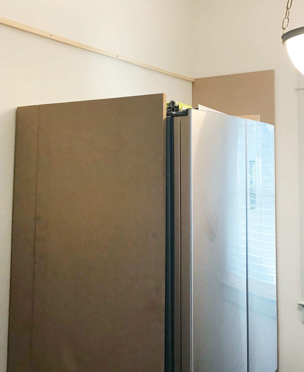 large MDF pieces brought in vertically against fridge in pantry