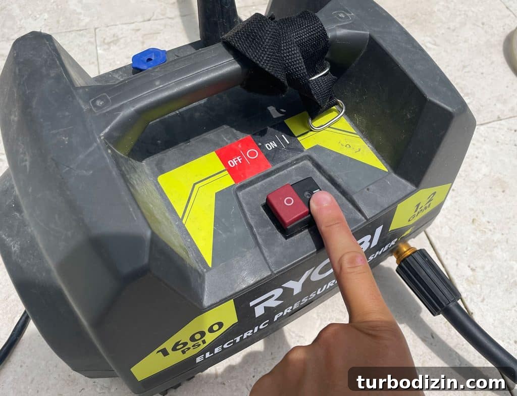Pressing power button on Ryobi electric pressure washer