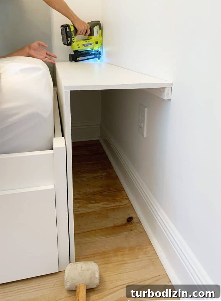 Build a Sturdy Bookshelf: Step-by-Step DIY Guide for Any Room 6 Painted pieces of MDF being nailed in for bottom shelf of built-in bookcase