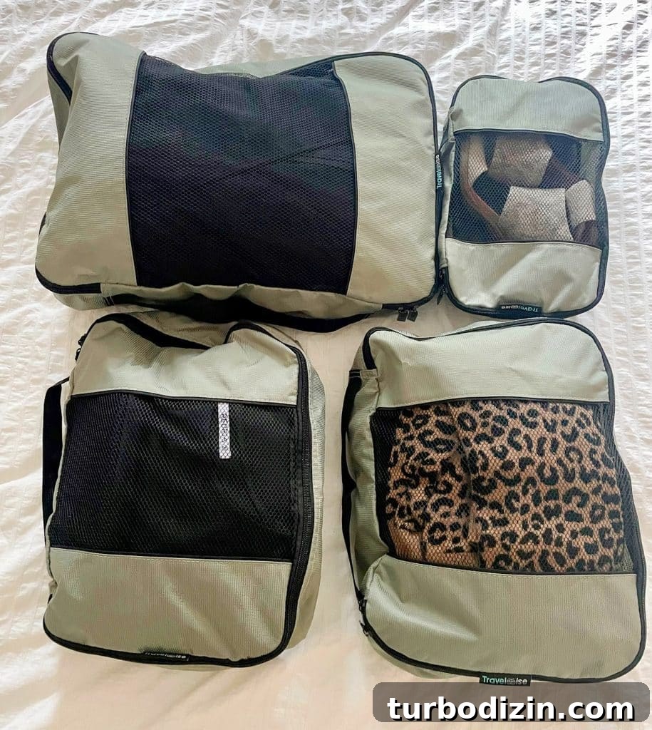 Gray zippered packing cubes on bed with minimal outfits for international trip to France