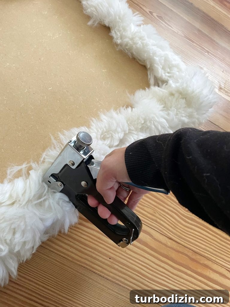 DIY Faux Sheepskin Seat Cushion: Step-by-Step Sewing Guide 5 Sherry stapling old sheepskin rug around loveseat base to upholster