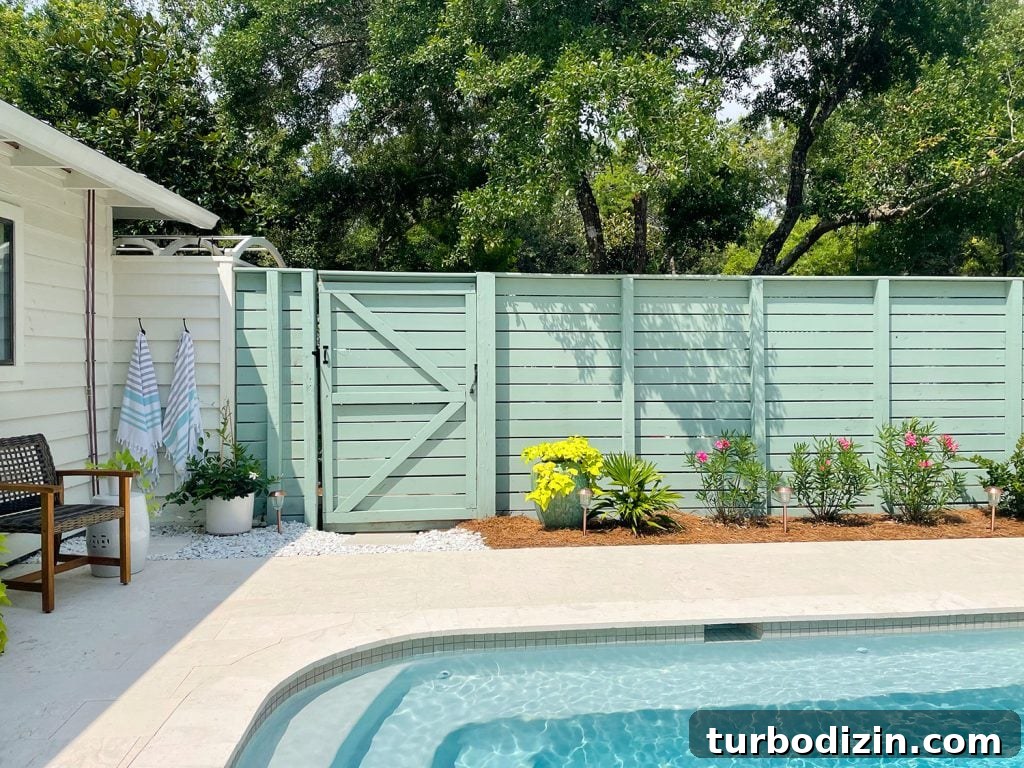 How We Transformed and Doubled Our Backyard Pool Area Space 5 Green fence connected to outdoor shower next to backyard pool