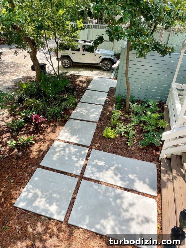 Large paver walkway leading to Jeep parked in gravel driveway