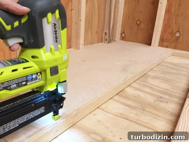 nailing plywood panel onto the bottom level of scrap wood storage organizer