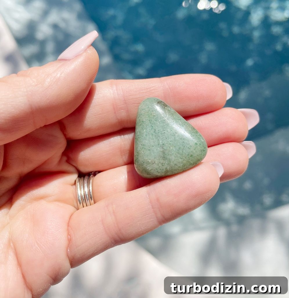 Green Aventurine Meaning & Properties: Uses, Benefits, and Care 4 Hand holding green aventurine polished gemstone over water