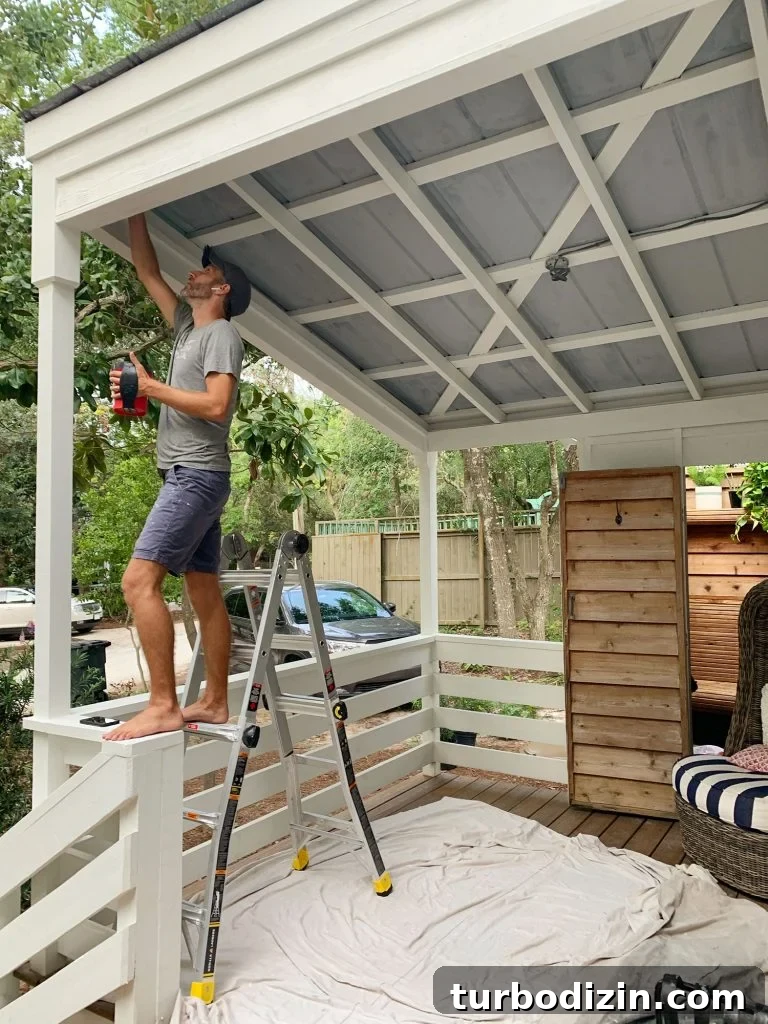 Top 12 Haint Blue Paint Colors for Southern Porches 12 John Standing On Ladder Priming Metal Porch Ceiling
