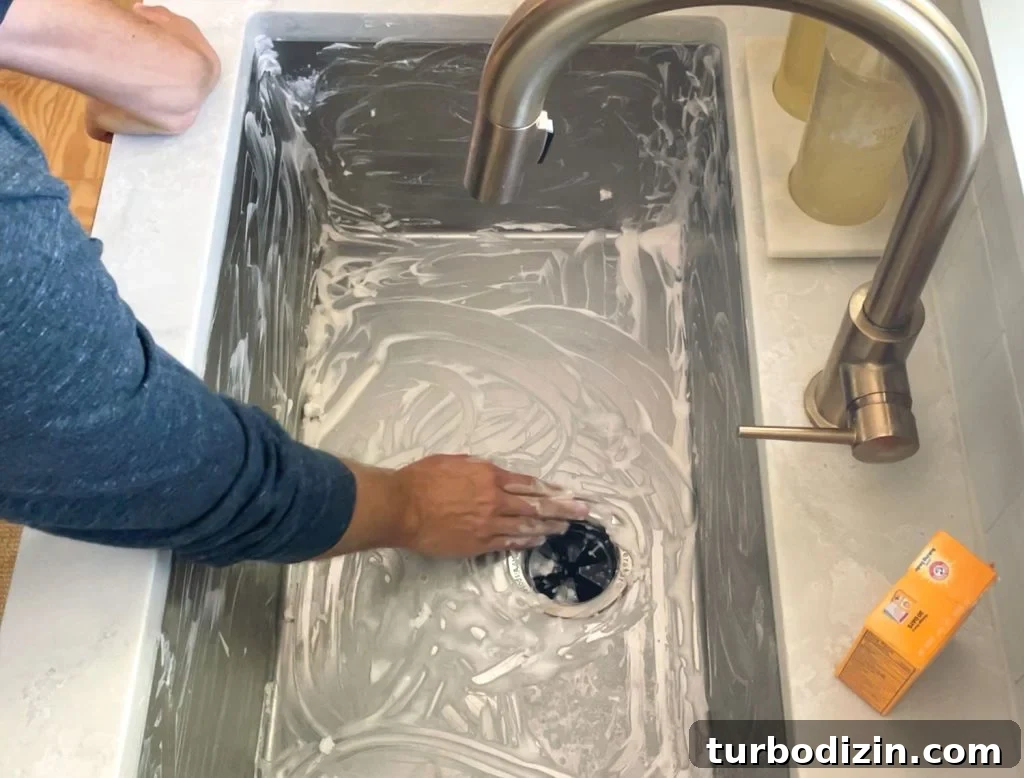Hand scrubbing a stainless steel sink clean with baking soda