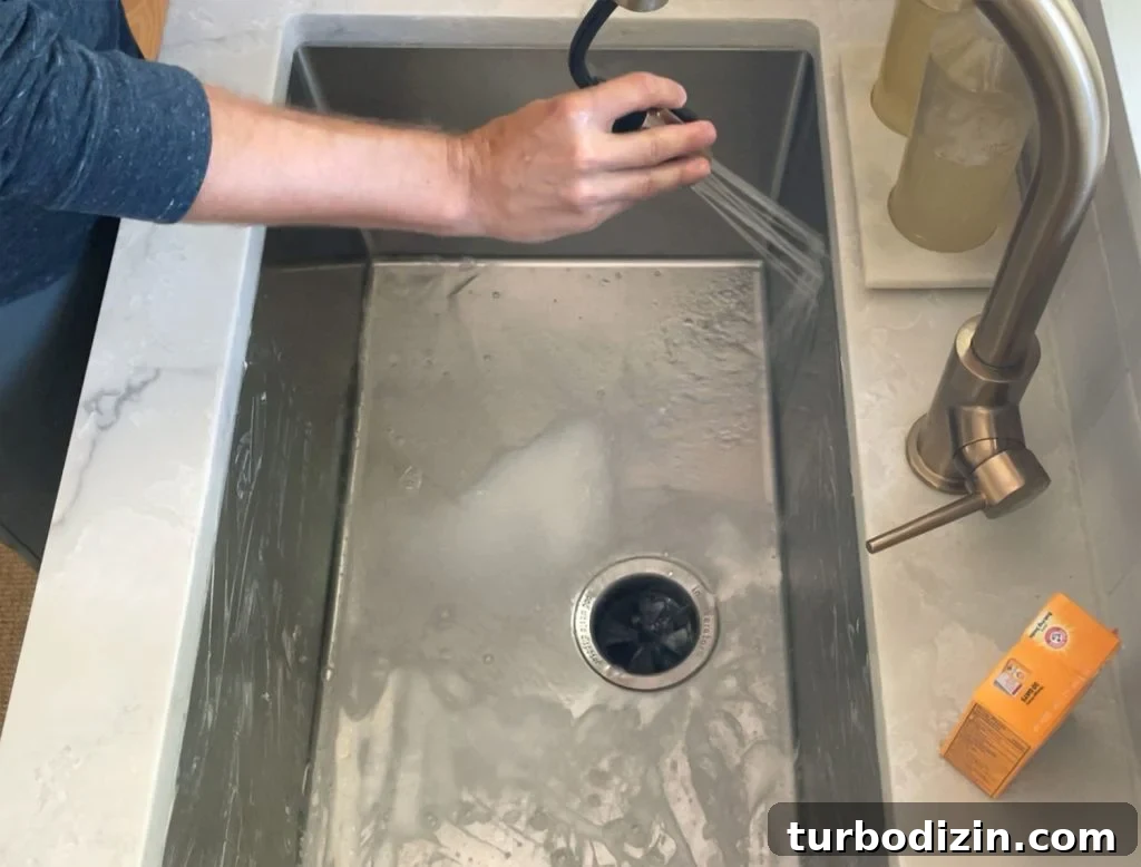 Rinsing stainless steel sink with warm water from faucet