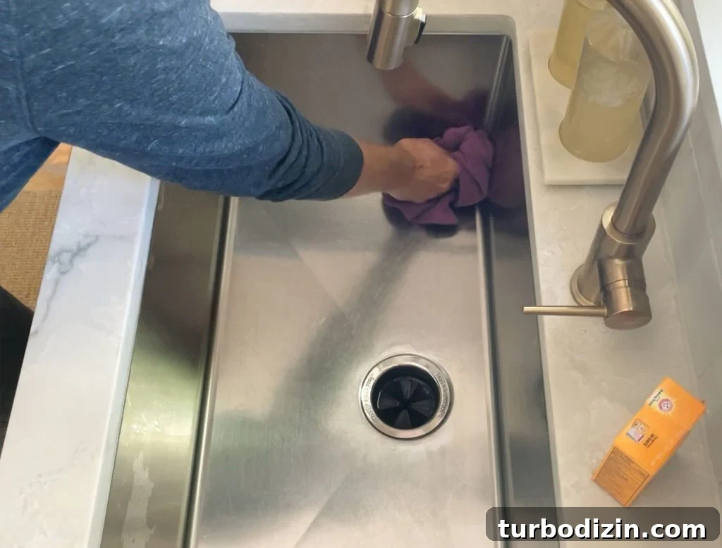 Buffing cleaned stainless steel sink dry with rag