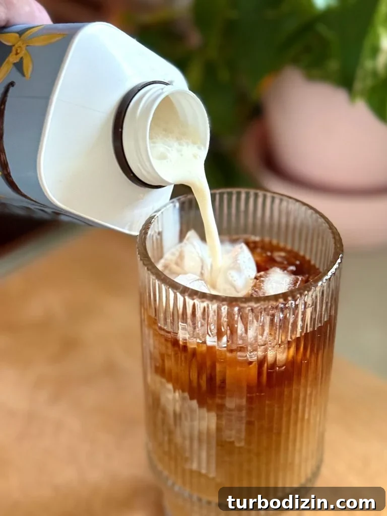 Cold Brew Coffee at Home: Step-by-Step Guide for Smooth Flavor 11 Pouring Creamer Into Glass of Iced Cold Brew Coffee Made At Home